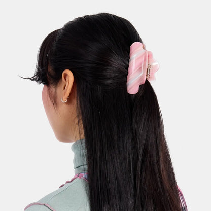 Person with long black hair wearing a pink hair clip on a white background