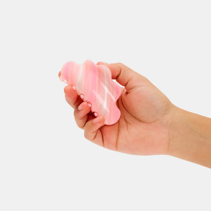 Hand holding a pink and white wavy hair clip