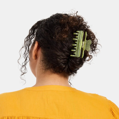 Person with a green hair clip in their curly hair against a white background