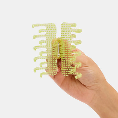 Hand holding a clear and lim e green hair claw 