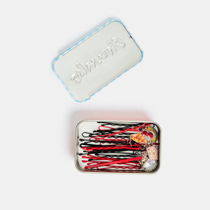 Set of hair pins in a small metal case with a branded lid on a white background