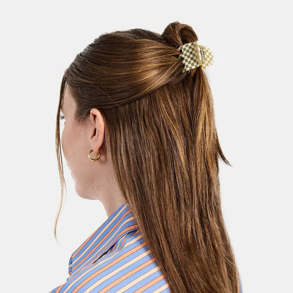 Woman with a high ponytail held by a decorative hair clip against a white background