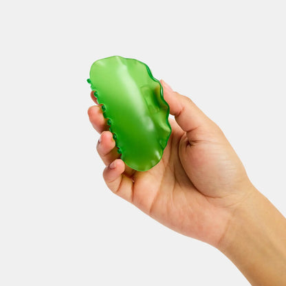 Hand holding a green hair clip against a white background
