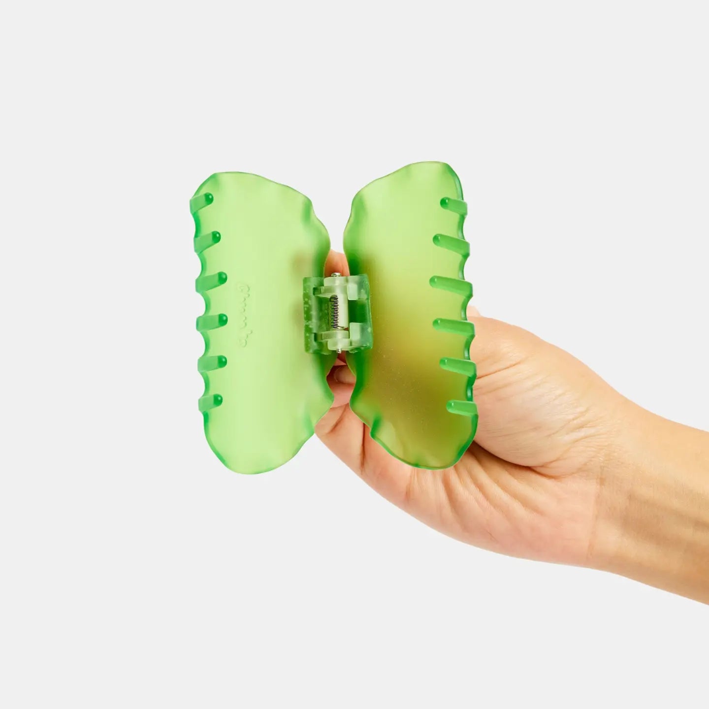 Hand holding a green butterfly-shaped object against a white background