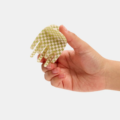 Hand holding a small checkered comb against a white background