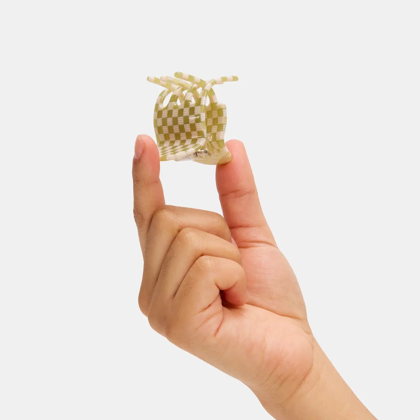 Hand holding a small hair clip with a checkered pattern